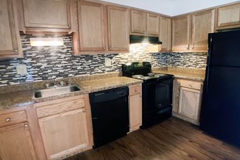A kitchen with wooden cabinets and black appliances.